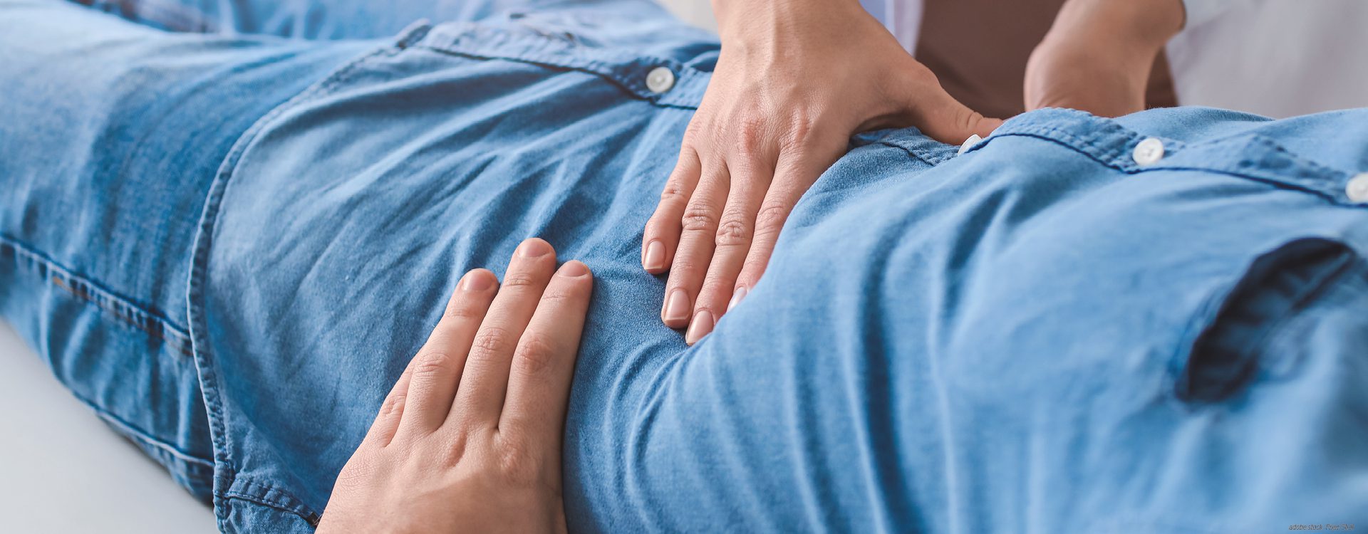 Zwei Hände untersuchen den Bauchbereich eines Patienten.
