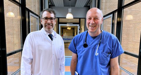 Prof. Dr. Christian Könecke (links) und Prof. Dr. Ulrich Kaiser stehen in einem Gang aus Fenstern und werden in Zukunft die Medizinische Klinik II zusammen leiten.