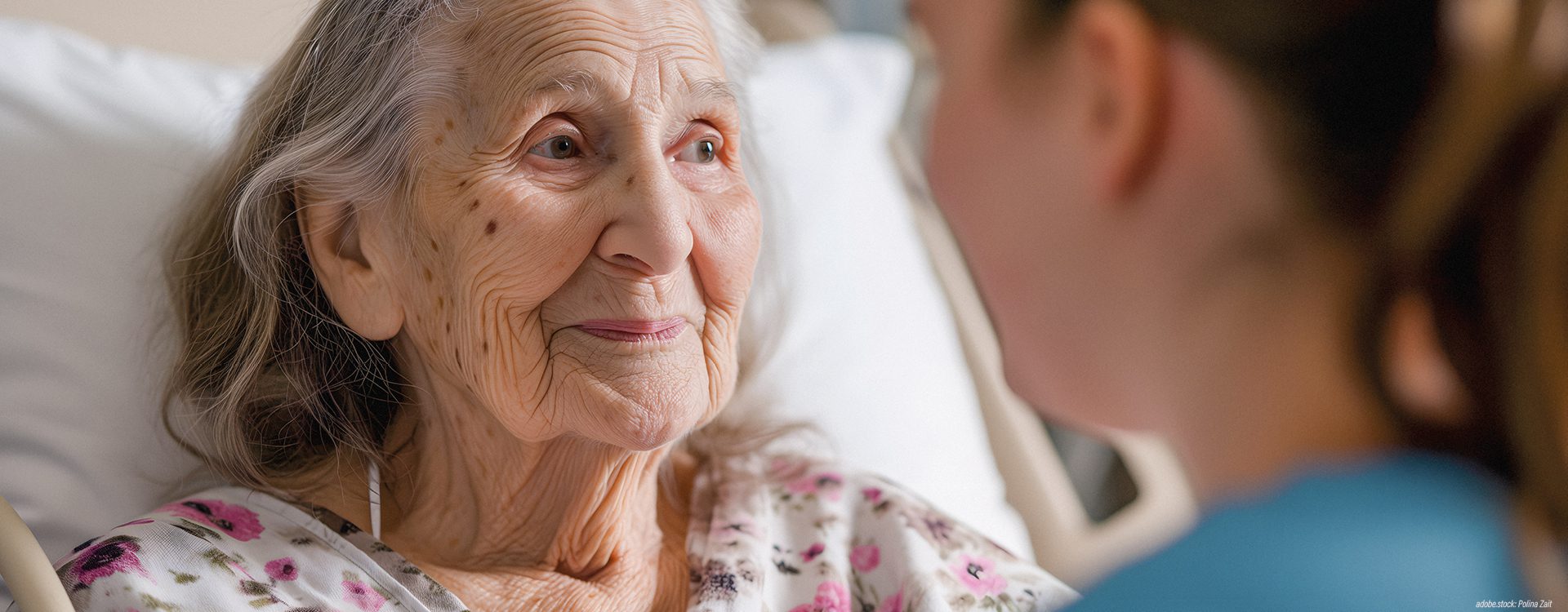 Eine weibliche Pflegekraft am Bett einer betagten Patientin