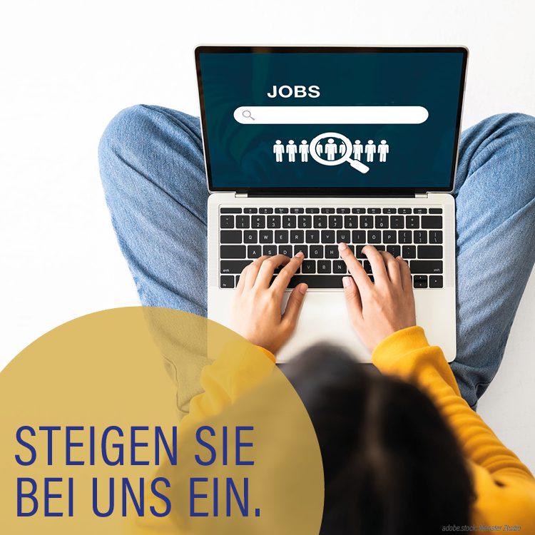 Person von oben aufgenommen, bedient am aufgeklappten Laptop die Tastatur, Bildschirm mit der Aufschrift Jobs, goldgelbe Kreise mit der Aufschrift steigen Sie bei uns ein