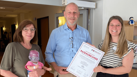 Ute Mordeja (links) und Hannah Fricke nehmen die Patenurkunde für die Schüttelpuppe von Jan Tangerding entgegen.